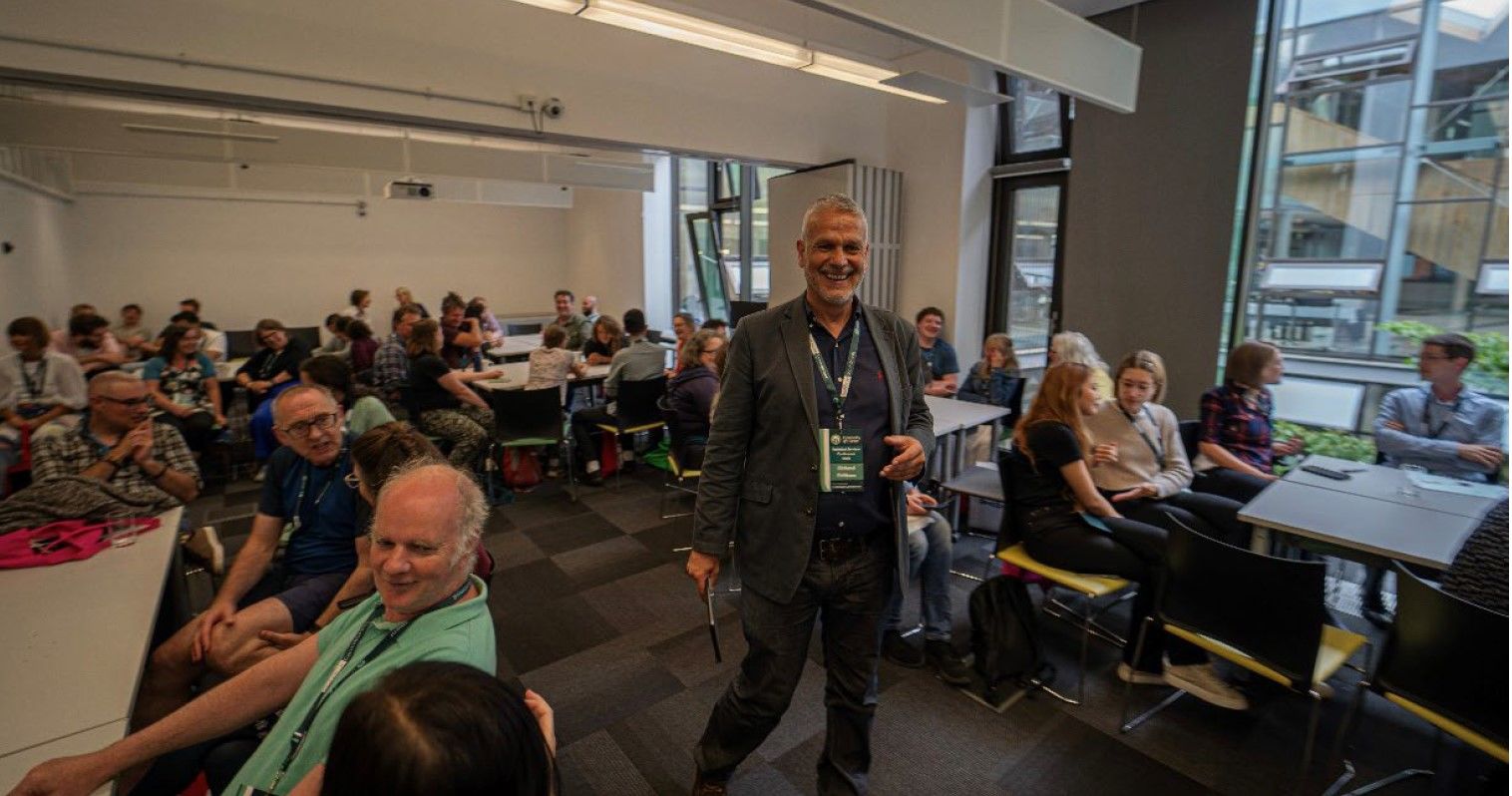 Man gives a talk and stands in a room full of people