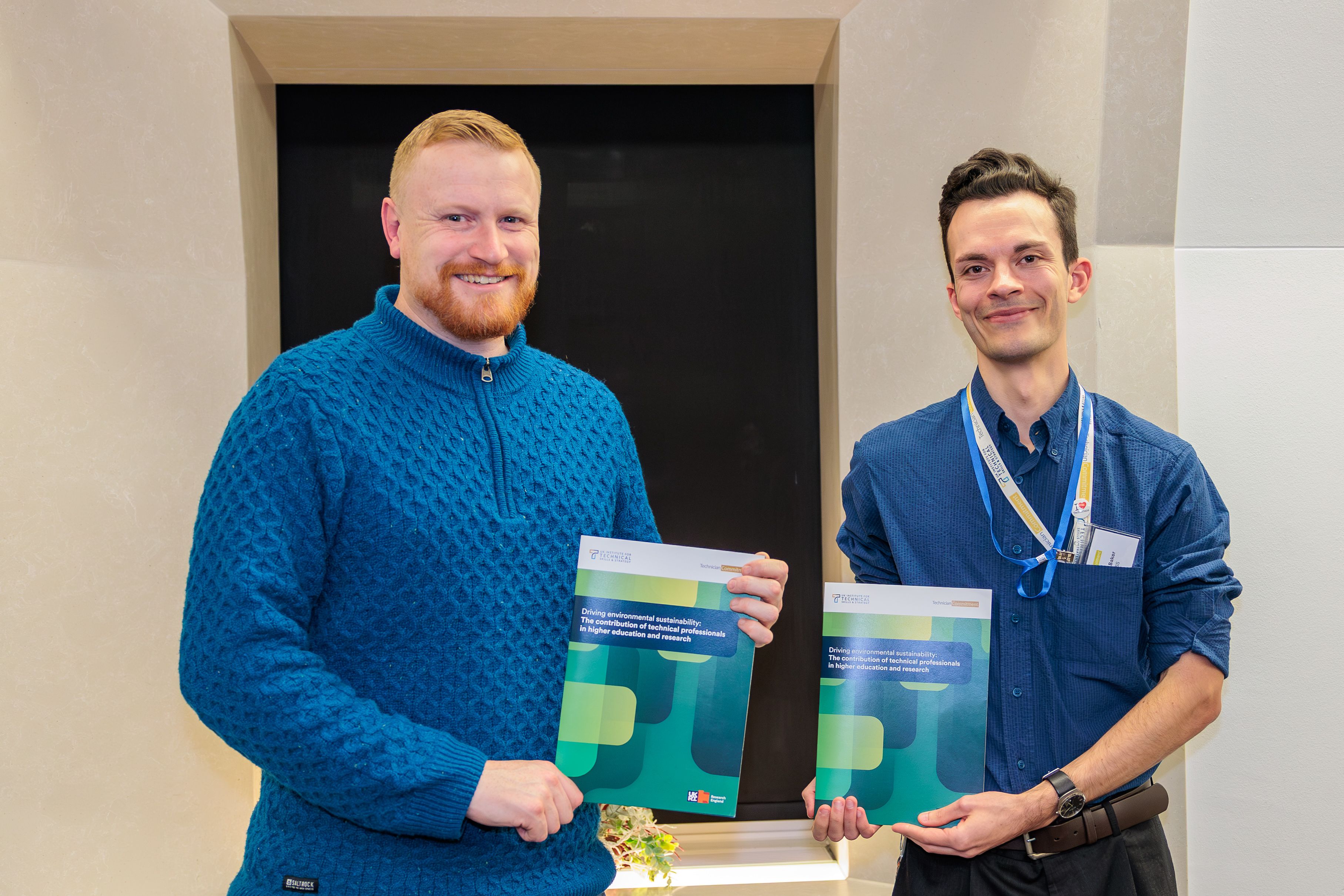UK ITSS Co-Director Ian Hancox and Research Fellow Charlie Baker smiling and holding hard copies of the newly launched report ' Driving Environmental Sustainability: The Contribution of Technical Professionals in Higher Education and Research'