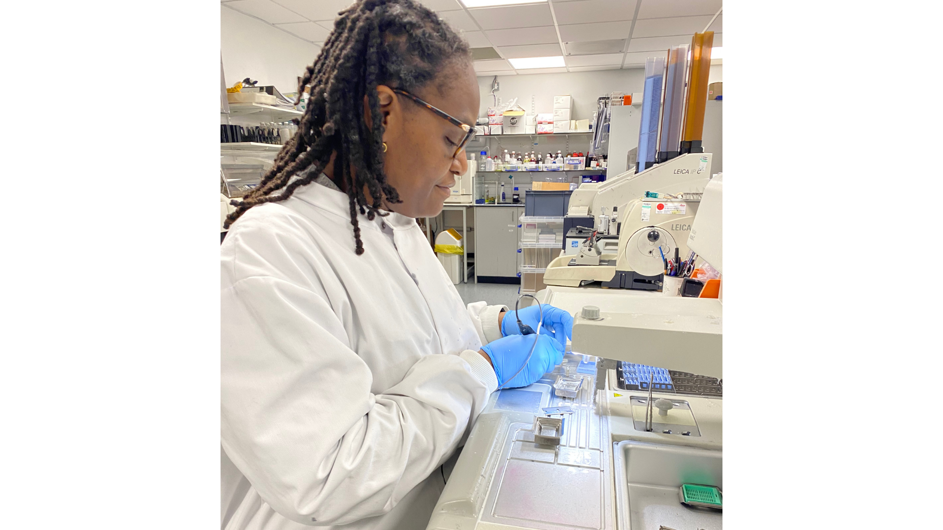 Nadia Rahman, Histopathology Laboratory Manager at QMUL BCI Pathology Core Facility, works at a histology workstation in a laboratory, wearing a lab coat and gloves as she carefully prepares tissue samples using specialised equipment. Surrounded by microtomes, slides, and laboratory materials, she carries out the precise technical processes that enable detailed microscopic analysis of biological tissues.